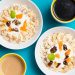 Top view of two breakfast bowls with bananas, yogurt, and coffee cups on a vibrant background.